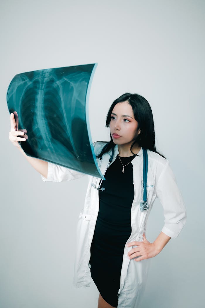 gallery-6 Young female doctor examining a chest X-ray with focus and professional attire.
