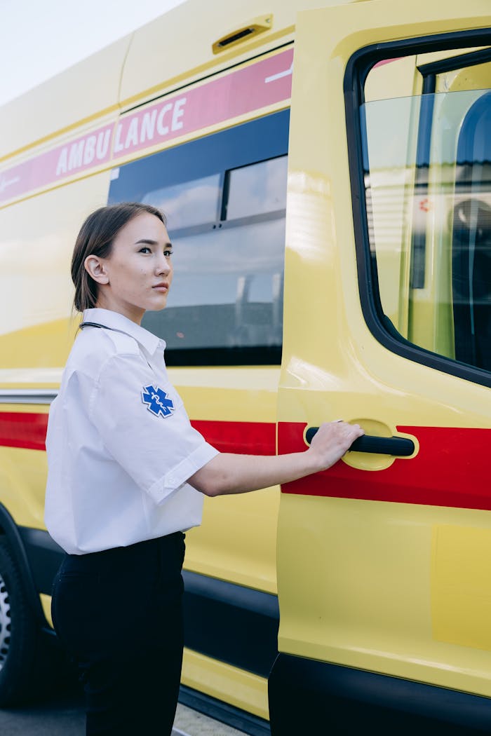 services-01 Young female EMT standing by an ambulance, ready for emergency response.